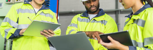 Workers in PPE holding clipboards and talking