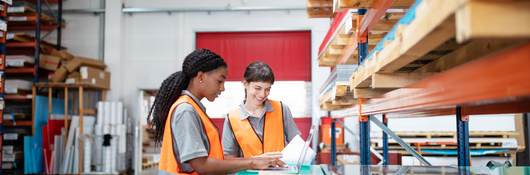 multi ethnic women workers working in a warehouse with a laptop.