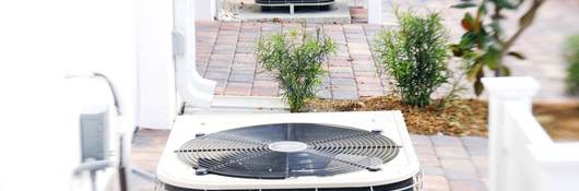 Row of air conditioning units on brick driveways.