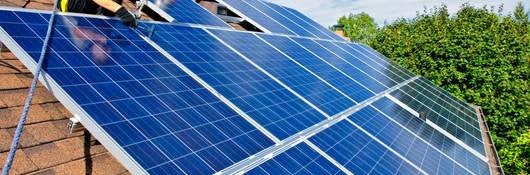 Construction worker on the roof of a house installing solar panels