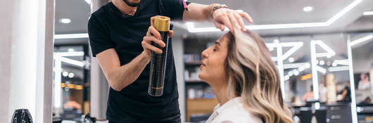 Hair stylist spraying hairspray on customer