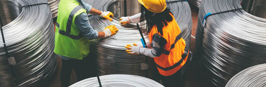 People working with large spools of wire in a warehouse