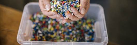 Man with container holding recycled plastic in factory