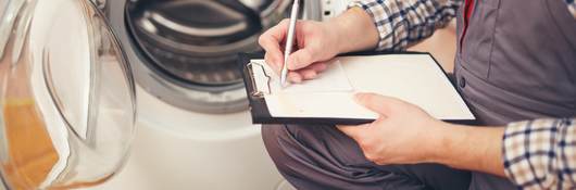 Repairman is repairing a washing machine.