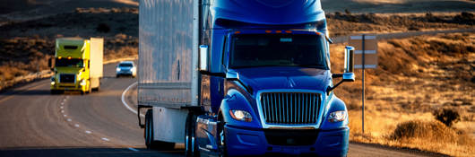 A semi truck driving down a highway at dusk