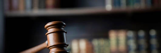 A judge's gavel on a wooden desk with books in the background