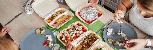 Family eating takeaway meals at home.