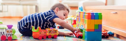 Little child, 2 years, playing with small cars and toys at home