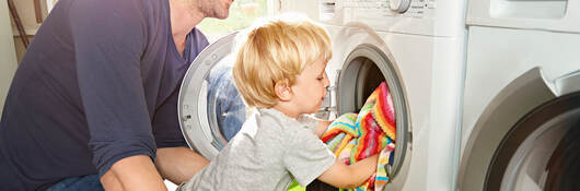 A parent and child loading a dryer