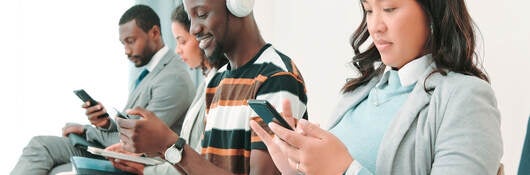 Several people in a waiting room and working on their smartphones