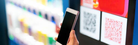 A person scanning a QR code for payment at a vending machine