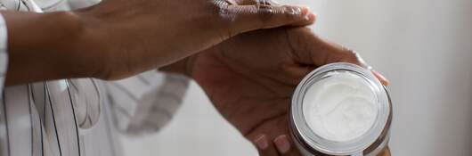 Hands of unrecognizable woman holding cosmetic cream.