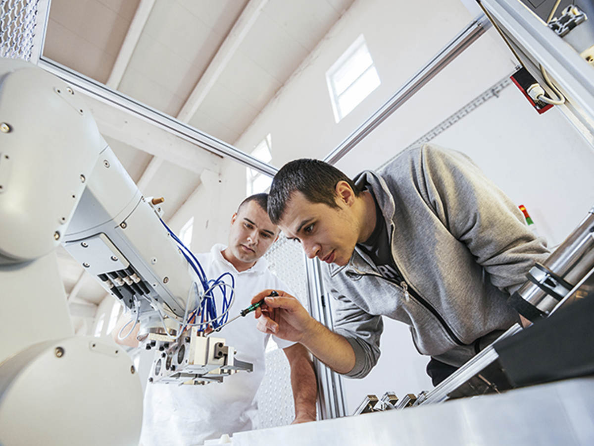 Two men work on robot.