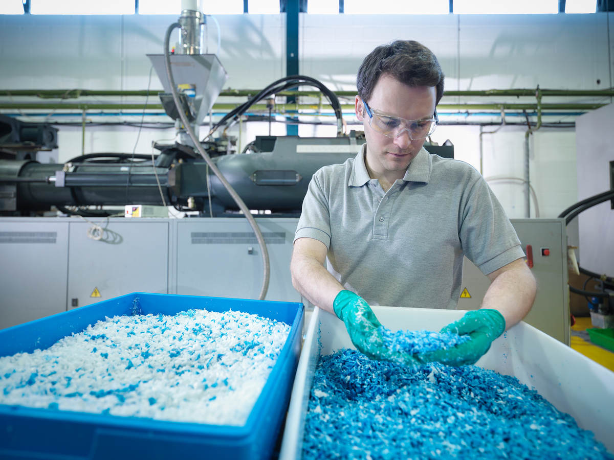 Worker inspecting recycled plastic in plastics factory