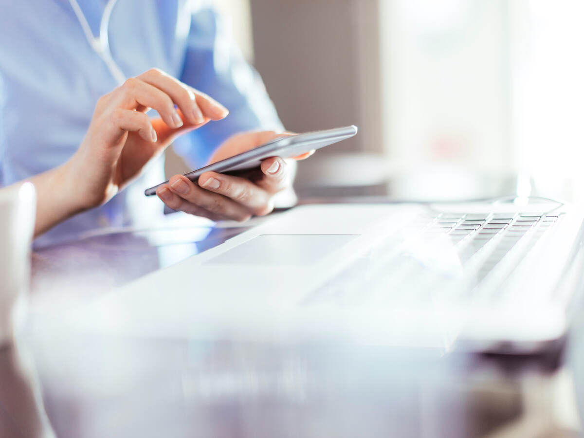 woman using a mobile phone in front of a laptop computer