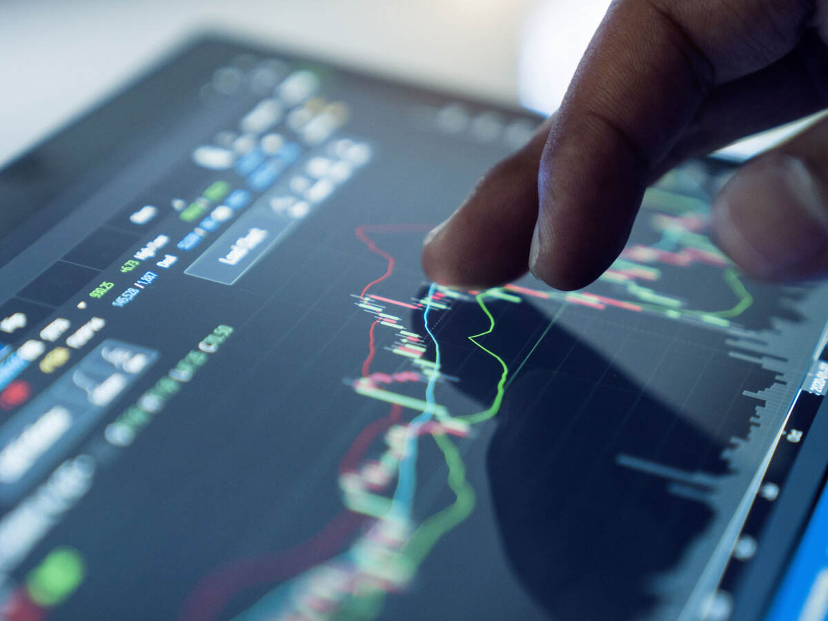 A hand interacts with a screen displaying data.