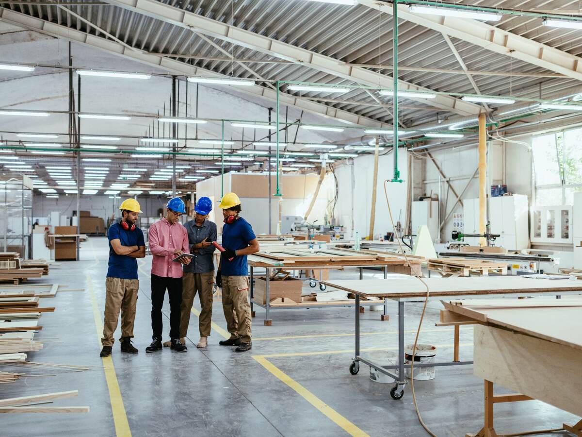 Architects, engineers and blue collar staff working together in modern factory.