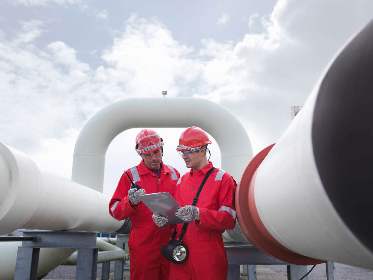 Two engineers having a discussion in front of pipes at a gas storage plant