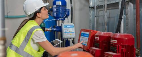 Female engineer doing quality control of water pumping engines in basement.