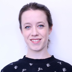 A pale-skinned woman with her tied back smiling in front of a white background.