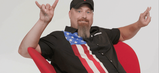 A Man Wearing Patriotic Shirt Sitting In Red Chair