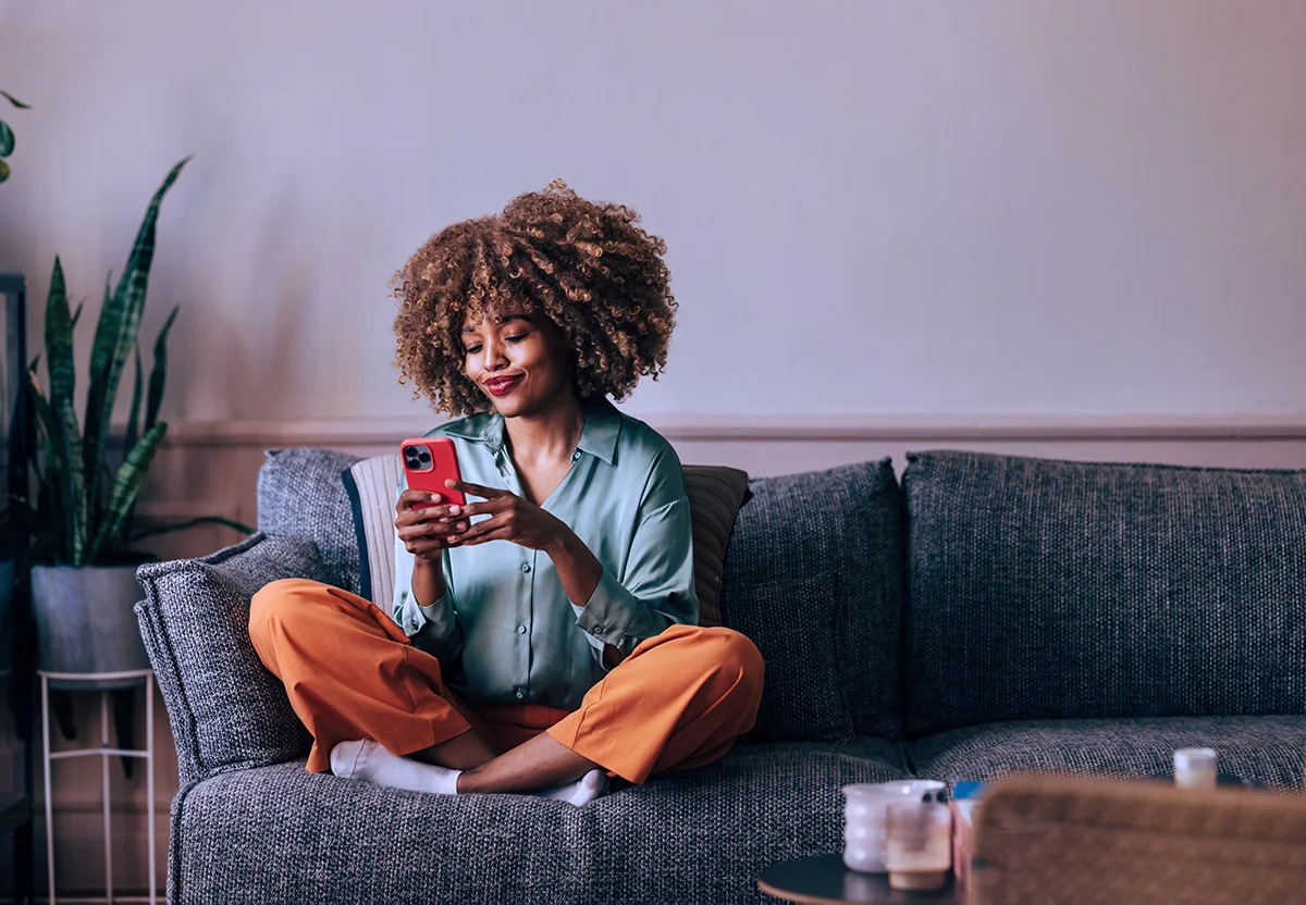 woman sitting on a couch using a smartphone