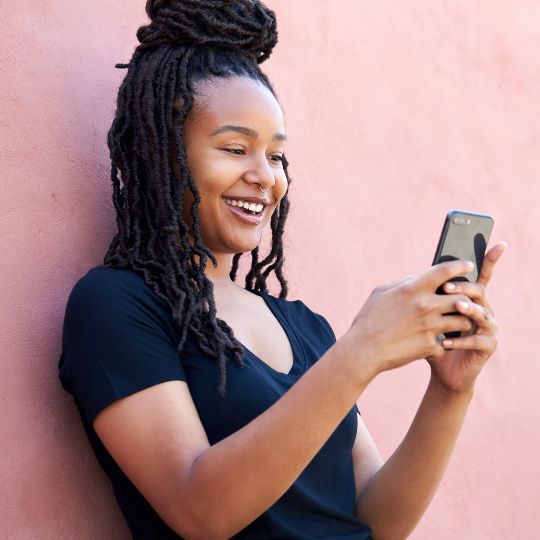 person using phone against a pink wall