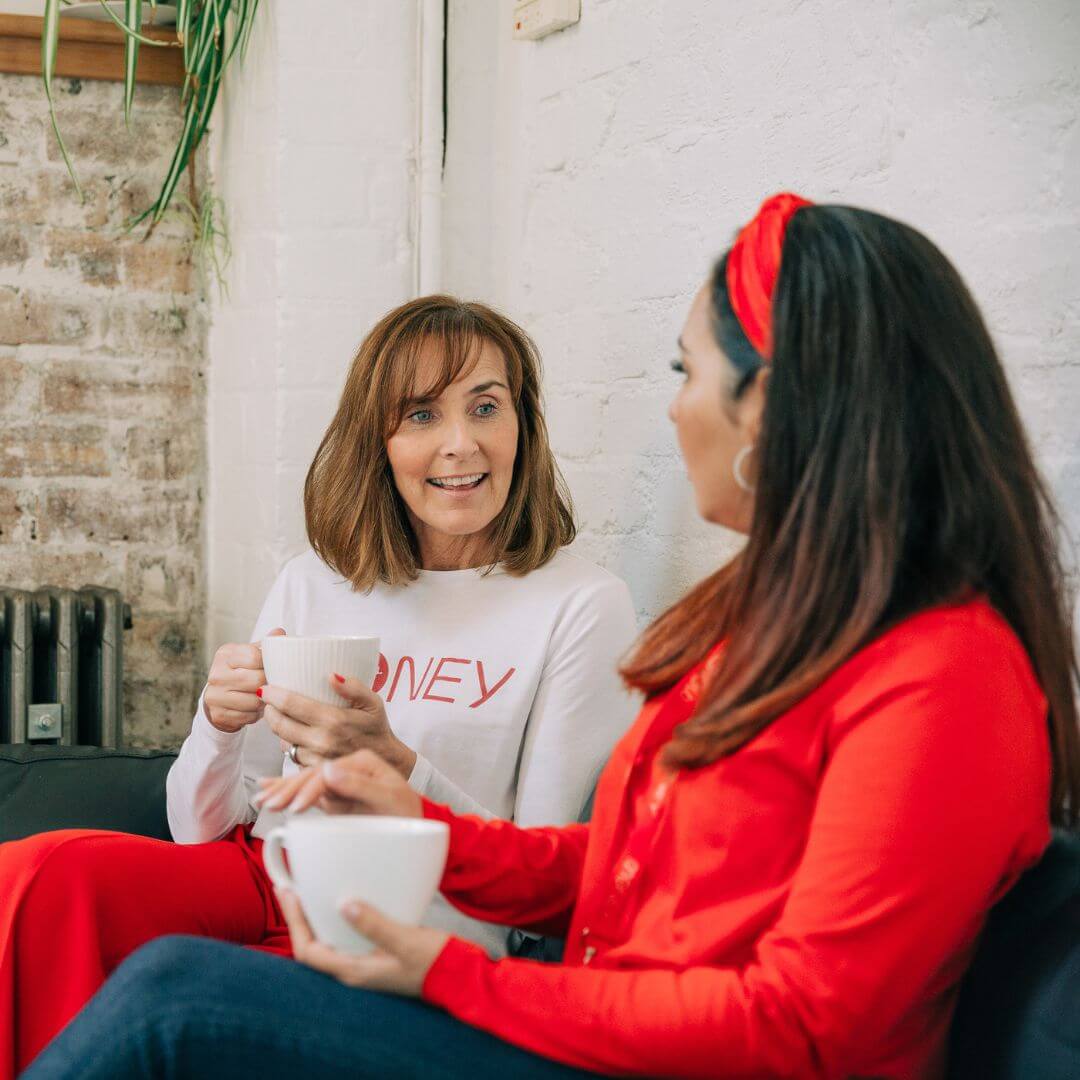 two people chatting on a sofa with a hot drink