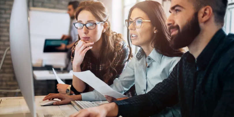 A team of performance marketers in front of a computer discussing scaling operations without added costs.