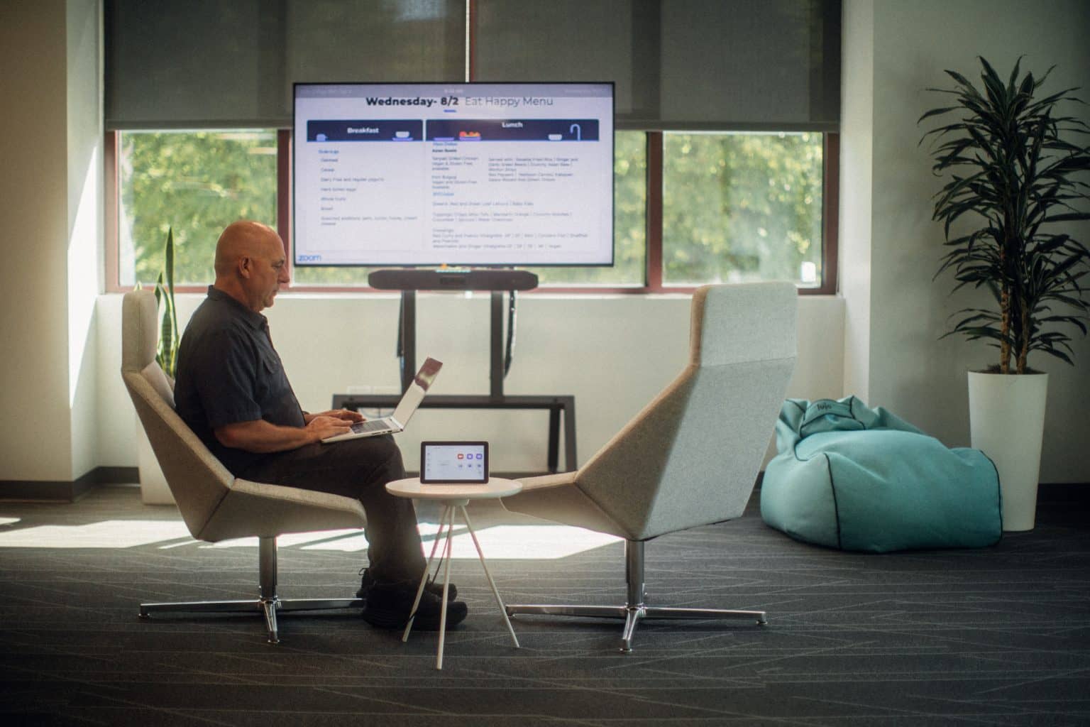 Man sits in front of a digital signage display showing the day's lunch menu.