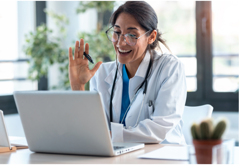 läkare som vinkar i ett zoom-samtal på en laptop