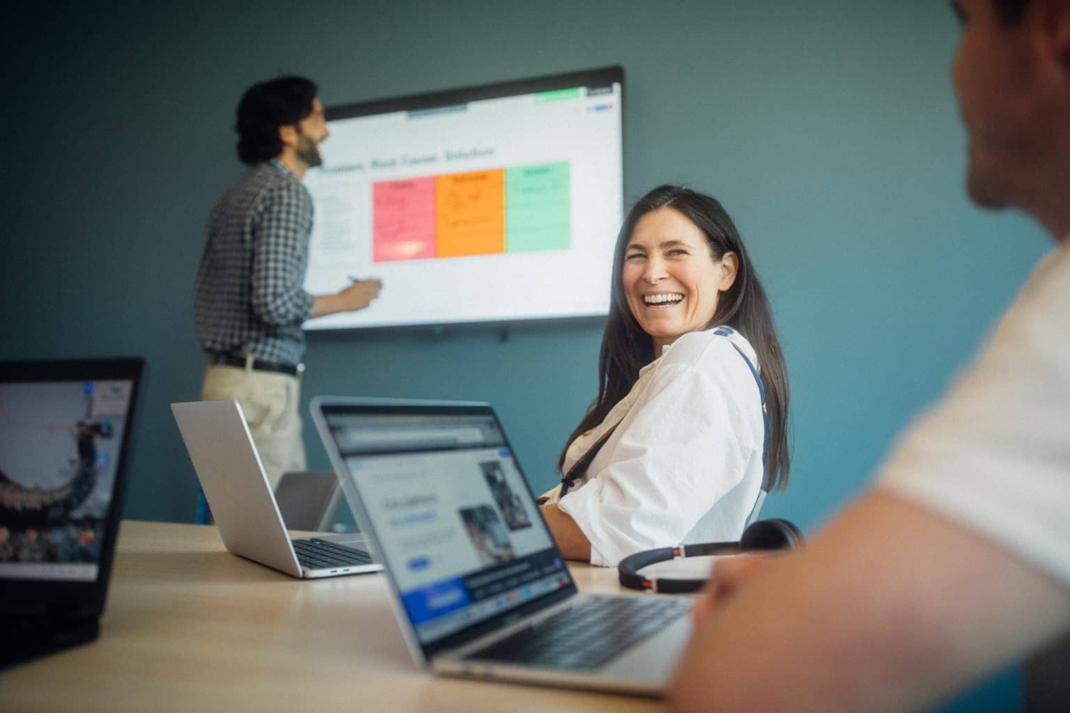 Employees in a conference room collaborating on a digital whiteboard