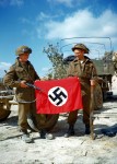 These two Canadian soldiers raise a Nazi flag which they captured in a quarry south of Hautmesnil, France. (August 10, 1944). Source: National Archives of Canada.