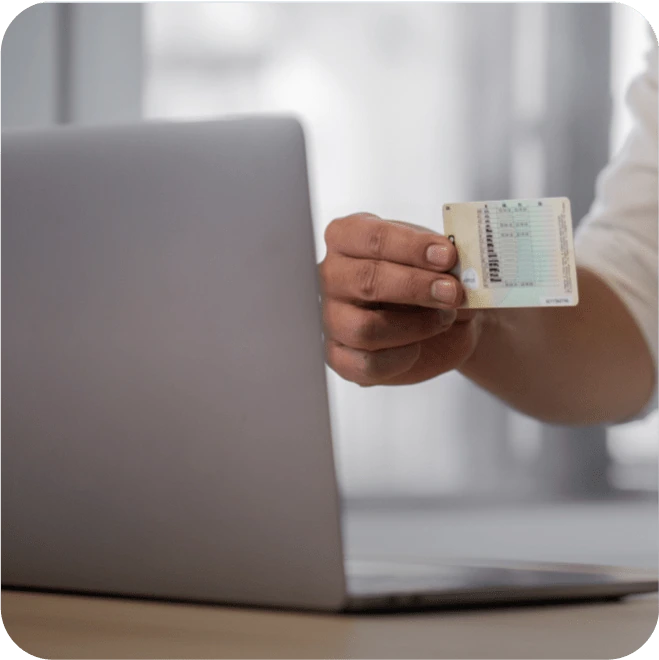 A person showing the back of their UK driving licence to their laptop webcam