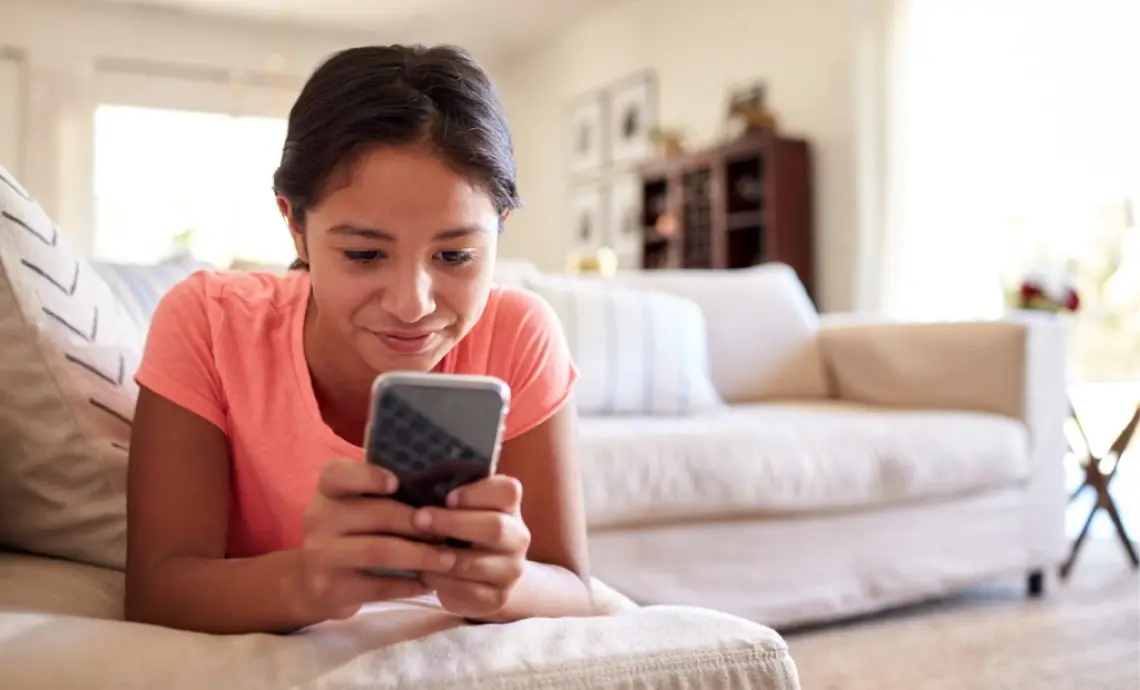 Girl relaxing on sofa using smartphone