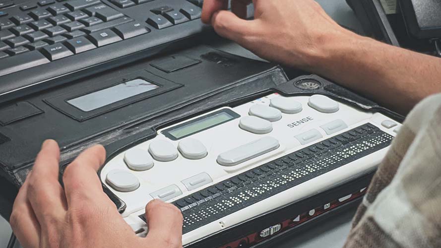 Hands touching a Braille Reader connected to Windows PC