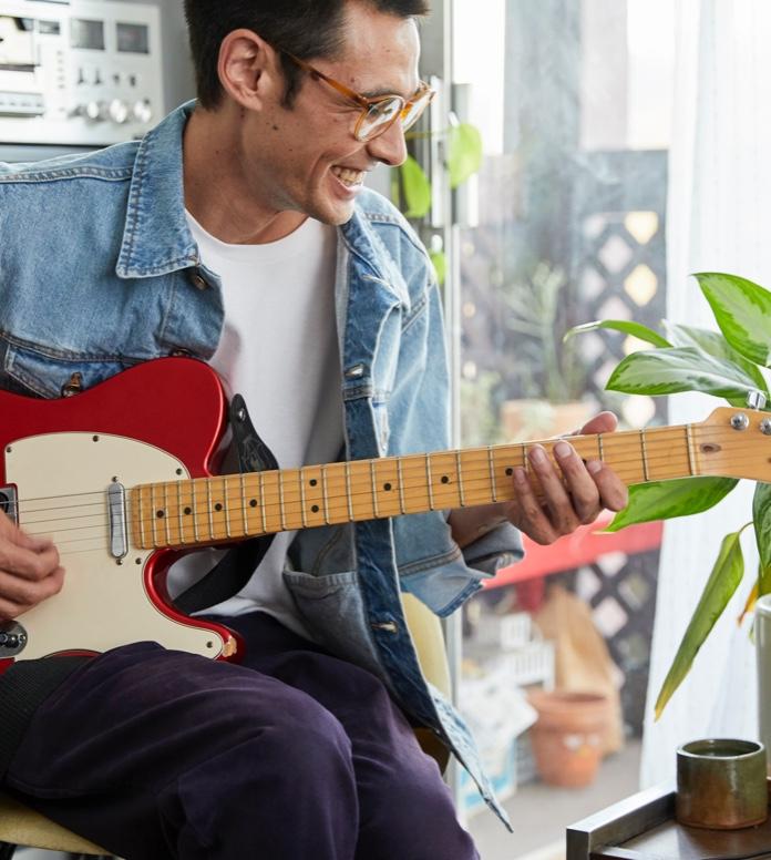 A happy guy playing the guitar with Yousician app