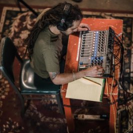 A creator seated at a table wearing headphones while using a Zoom Livetrak L-12.