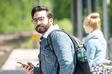 Ein Fahrgast mit dem Smartphone am Bahnhof stehend