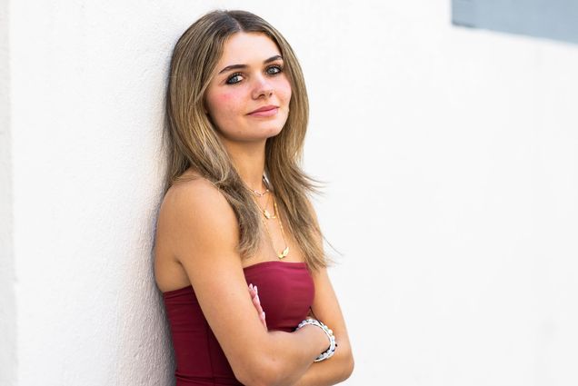 Photo: Camille Cattaui (CAS'28), a white woman with medium length highlighted hair, poses for a photo against a white wall.