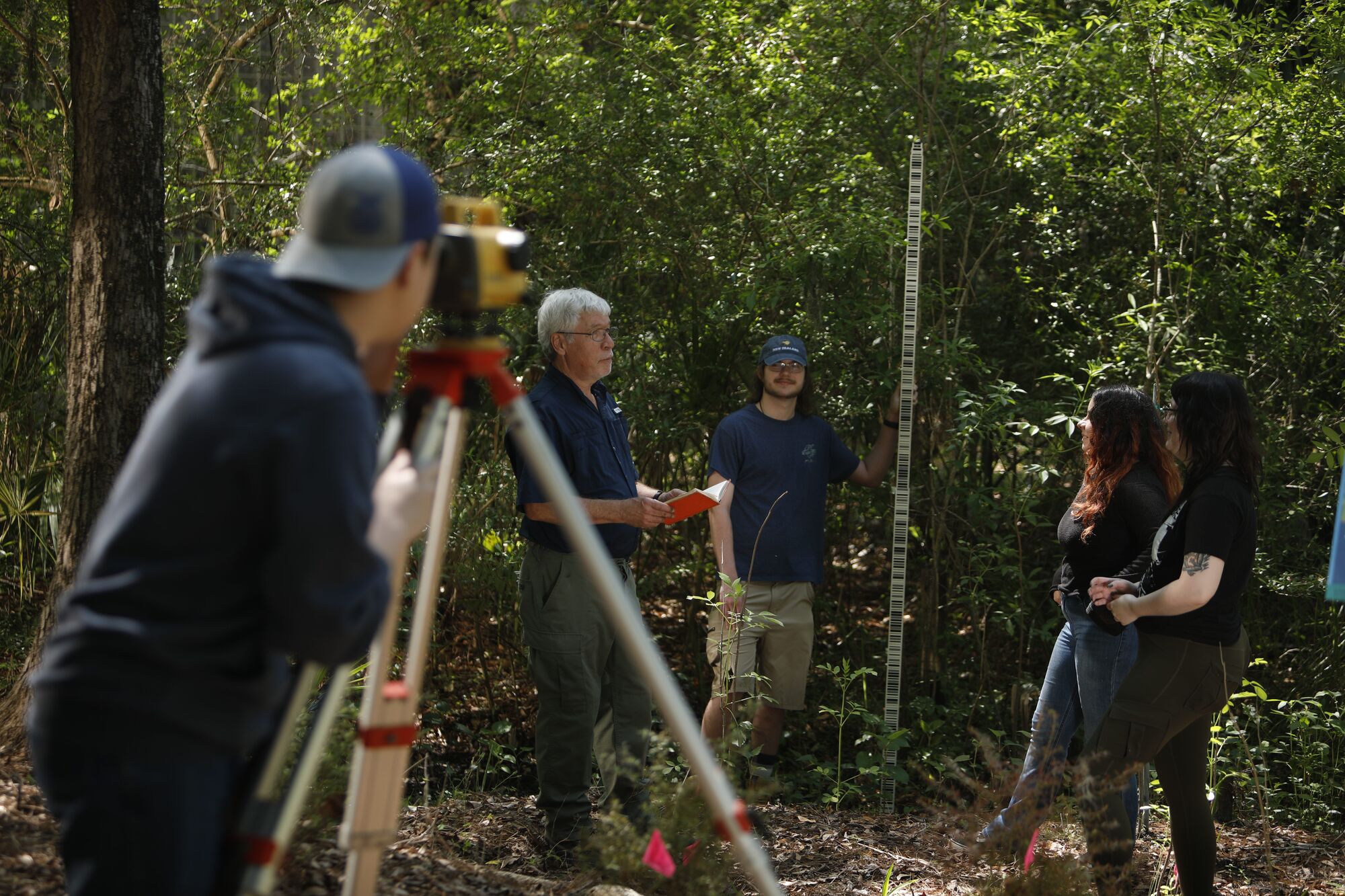 Surveyor in wooded area with three other people