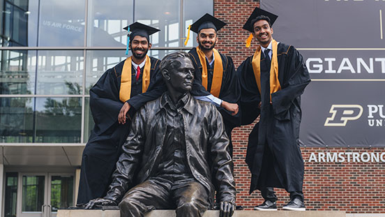 Purdue University students standing in front of Neil Armstrong statue.