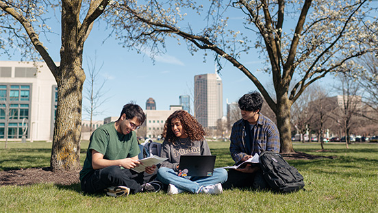 Group of students sitting under a tree in downtown Indianapolis. 