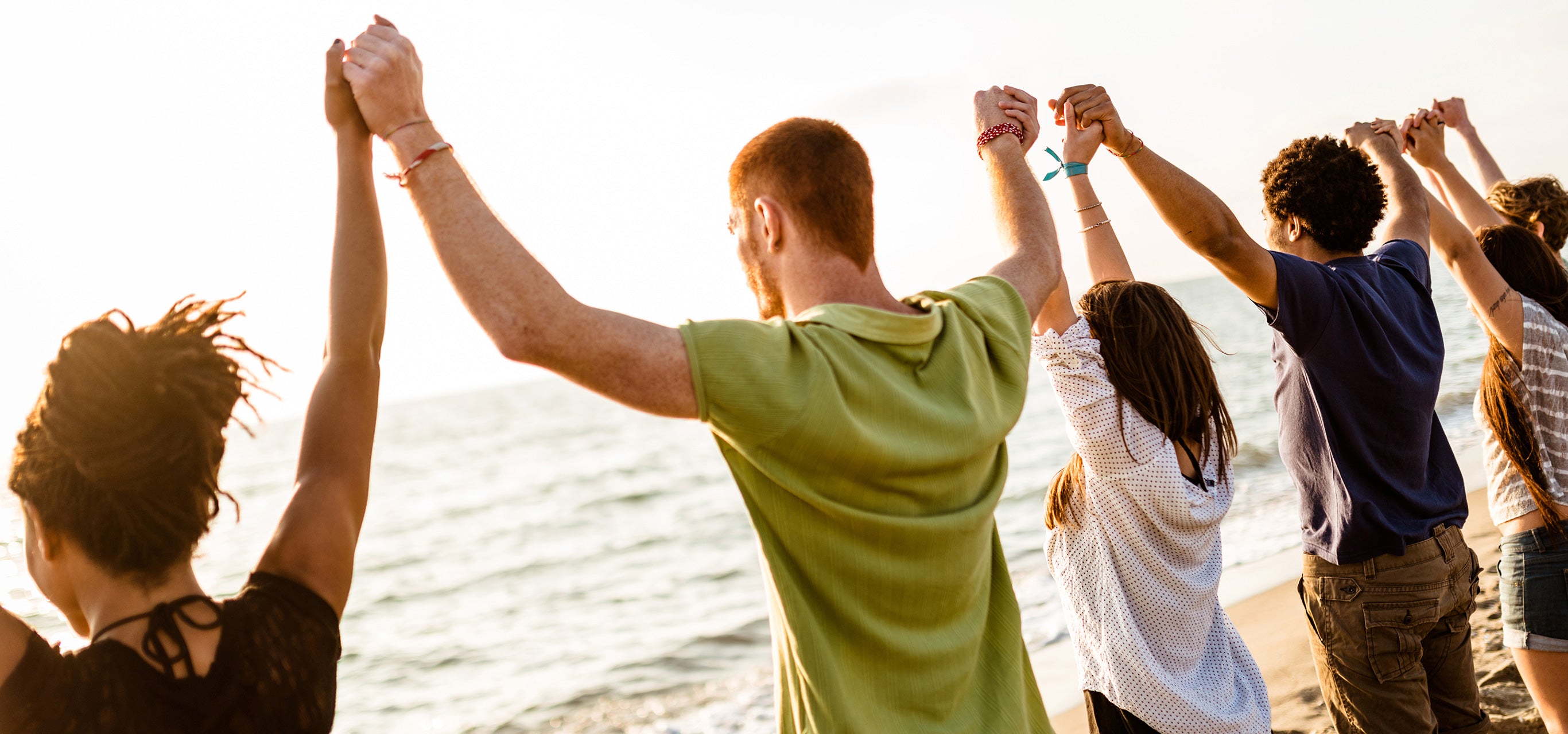 Students link hands and share a moment while looking out at the ocean.