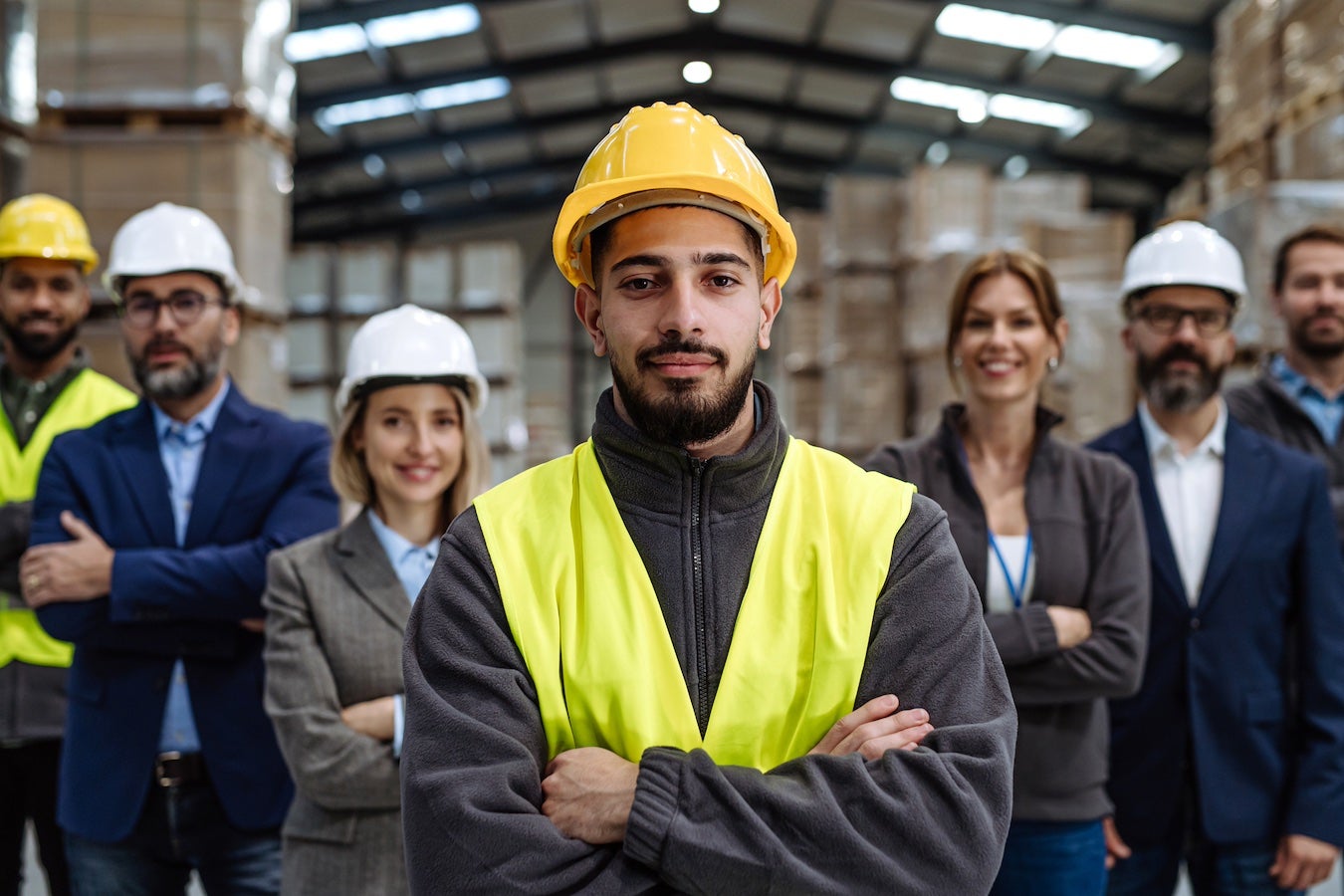 Photo of warehouse worker with managers and directors in background