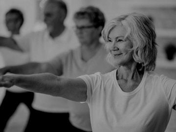 A senior woman is smiling while stretching out her arms.