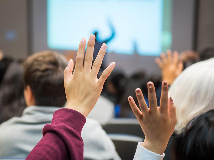 Students raising their hands in a classrom setting