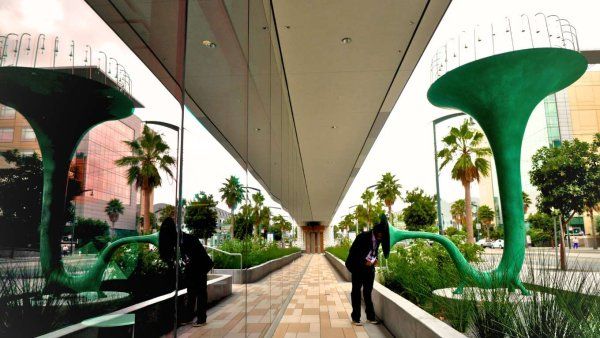 view of green trumpet art sculpture reflected on mirror windows.