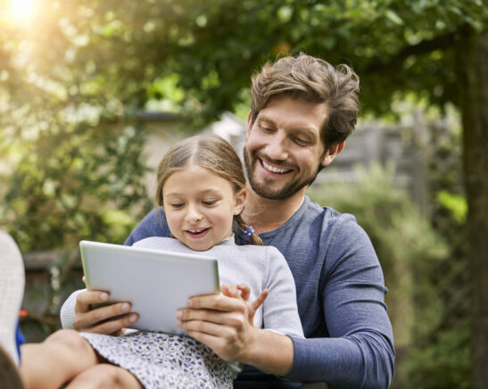 Happy father and daughter using tablet together in garden