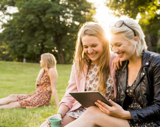 trois amis dans un grand jardin, l'un d'eux montre quelque chose sur le téléphone